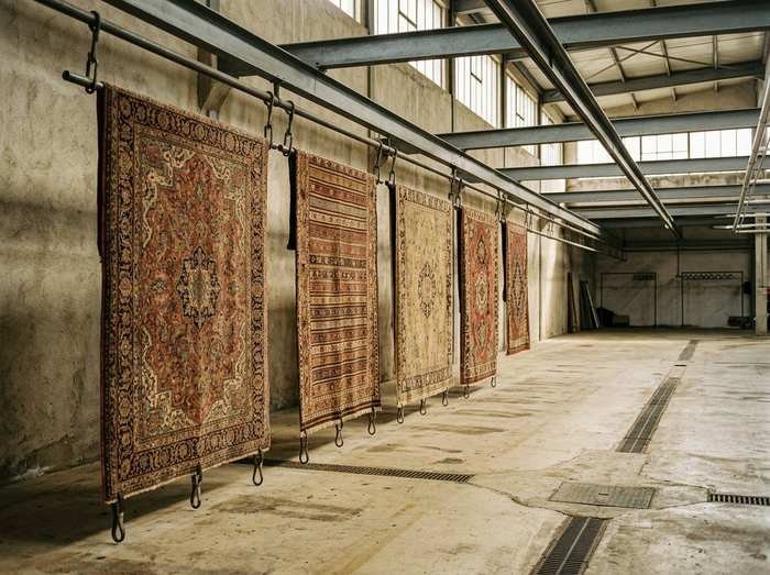 Séchoir de l'atelier : cinq tapis suspendus en enfilade à un rail d'acier, l'air passant entre eux