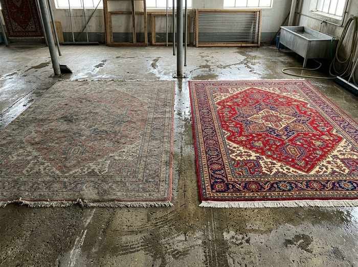 Deux tapis côte à côte sur l'aire de lavage : l'un sortant du bain, l'autre encore encrassé