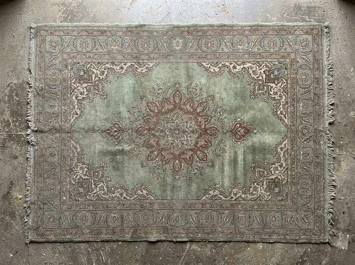 Tapis ancien à champ vert avant lavage : les couleurs sont ternies par la poussière