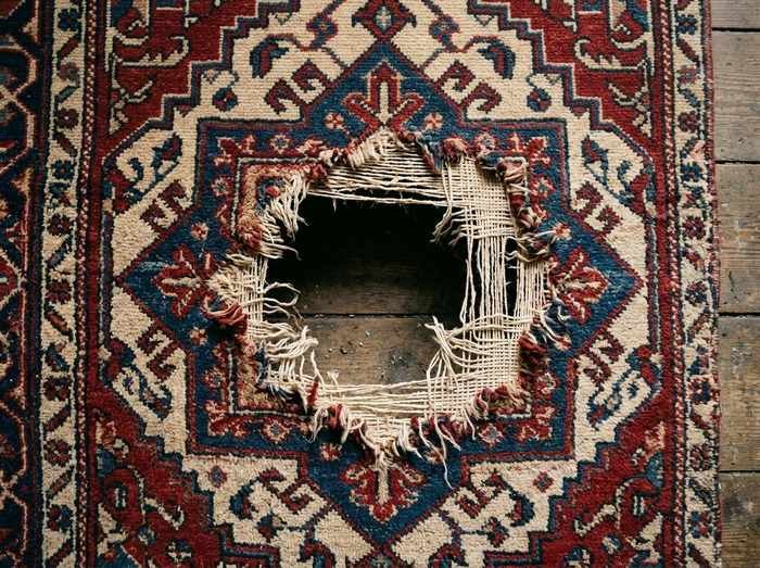 Tapis à bordure géométrique percé d'une lacune claire, avant retissage